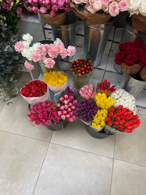 A display of multiple small flower bouquets arranged on a tiled floor, featuring a variety of brightly coloured flowers including red, yellow, pink, purple, and white. The bouquets are wrapped in whit