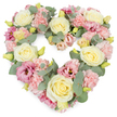 A tender heart-shaped wreath is pictured against a bright white background, its pastel flowers and soft foliage forming a compassionate tribute. The heart is fully defined by blooms, with no visible gaps, giving it a dense, luxurious presence and a clear, symbolic shape. Creamy ivory and pale yellow roses are scattered throughout as focal points, their full, spiralling petals opening gently to reveal velvety layers that suggest care and devotion. Around and between these roses nestle clusters of delicate, light pink carnations, their edges finely ruffled so that they create a cloud-like texture across the surface of the heart. Deeper magenta-pink and mauve lisianthus blossoms, with their slightly more open, trumpet-shaped forms and occasional darker centres, lend quiet complexity and a sense of depth, like moments of deep reflection during a farewell. Silvery eucalyptus leaves weave gracefully among the flowers, following the curves of the heart and adding a cool, muted green that contrasts beautifully with the soft pinks and creams. Small yellowish-green buds are scattered subtly through the arrangement, hinting at life still unfolding. The overall palette remains gentle and restrained, evoking peace, tenderness, and heartfelt sorrow. This kind of heart-shaped floral tribute feels particularly appropriate for funeral services and memorials in and around South Ruislip, perhaps resting beside a loved one at Breakspear Crematorium or in a local church near Station Approach, offering comfort and a visible expression of enduring love when words feel inadequate.